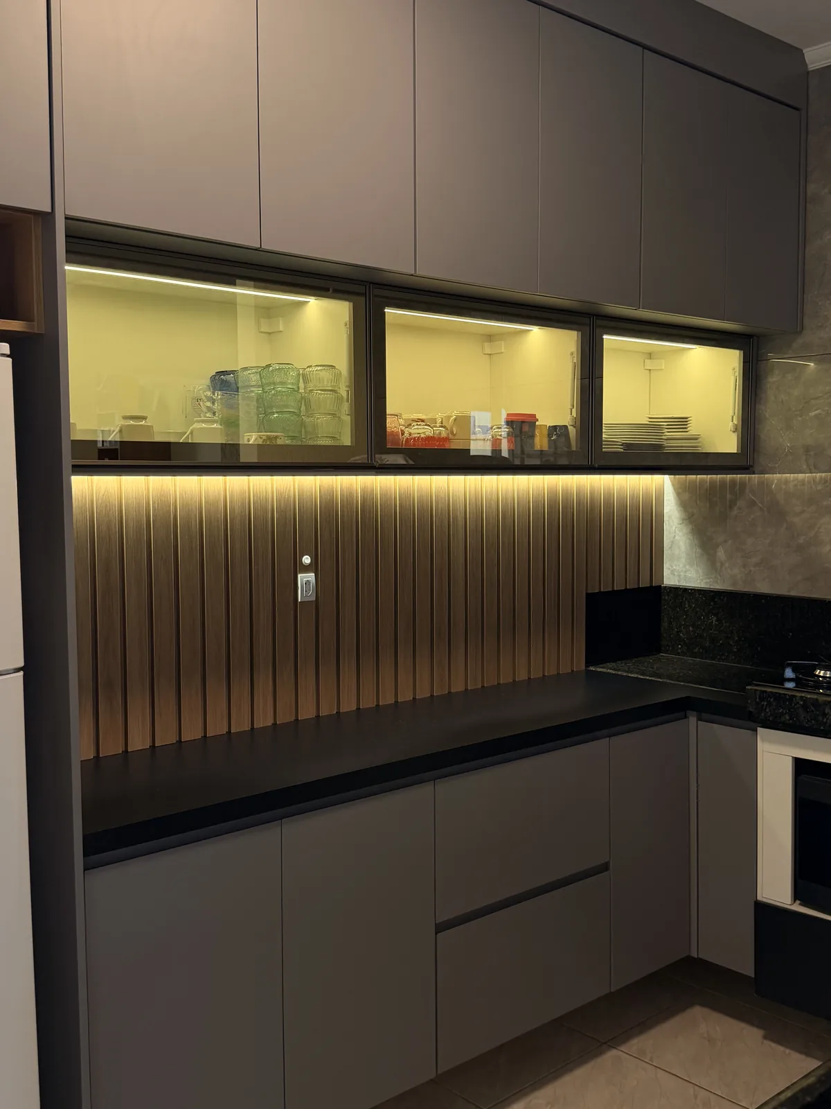 Cozinha planejada vertical com armários sob medida e bancada de trabalho.